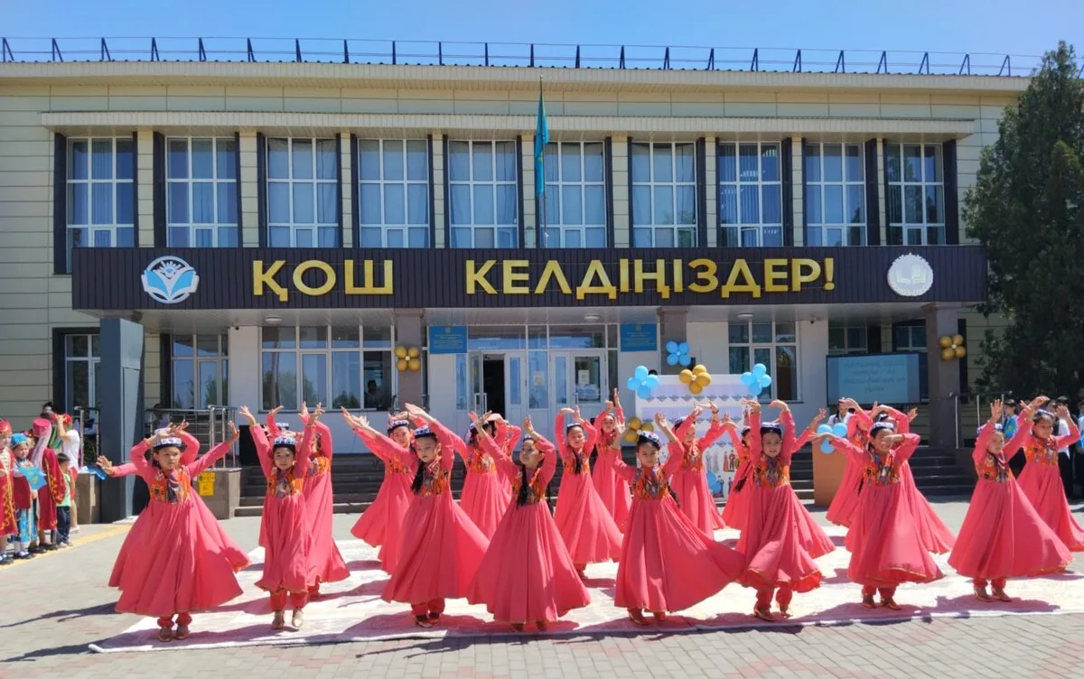 Школьники в национальных костюмах выступают на сцене в Жаркенте на празднике единства
