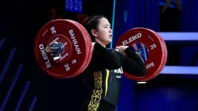 Казахстанская тяжелоатлетка поднимает штангу на соревнованиях в Талдыкоргане