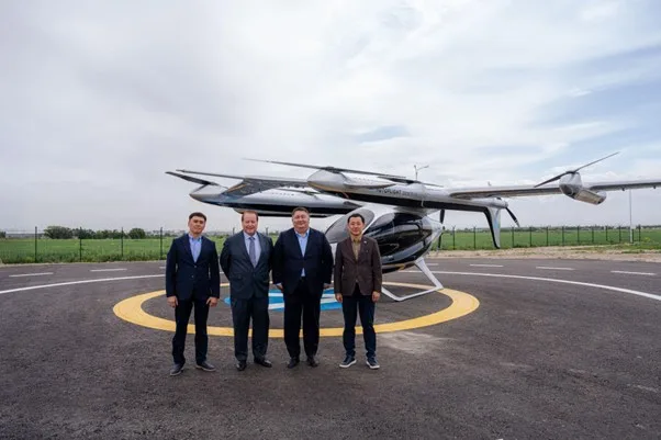 Современное аэротакси eVTOL поднимается в воздух над футуристическим городским пейзажем Alatau City.