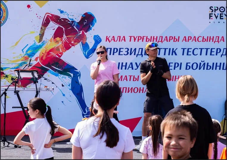 Группа людей занимается спортом на стадионе, готовясь к сдаче Тестов Президента Республики Казахстан в Алматы.