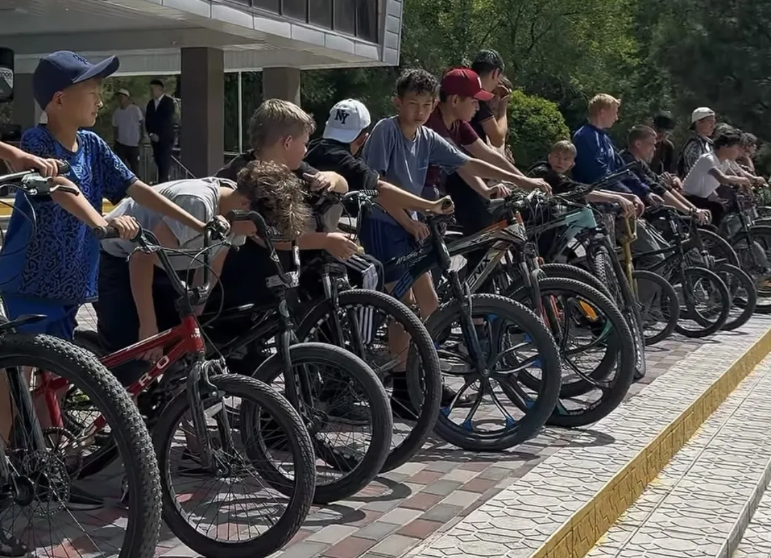 Участники велопробега в Текели едут по улице города, поддерживая здоровый образ жизни и спорт.