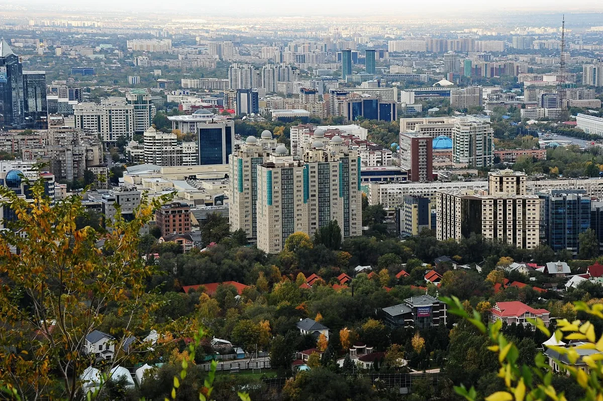 Дым от промышленных и жилых зданий загрязняет атмосферу города Алматы, покрывая его смогом.