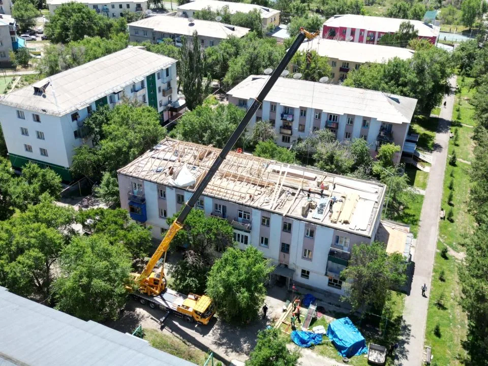 Рабочие ремонтируют крышу многоэтажного дома в городе Текели, область Жетісу