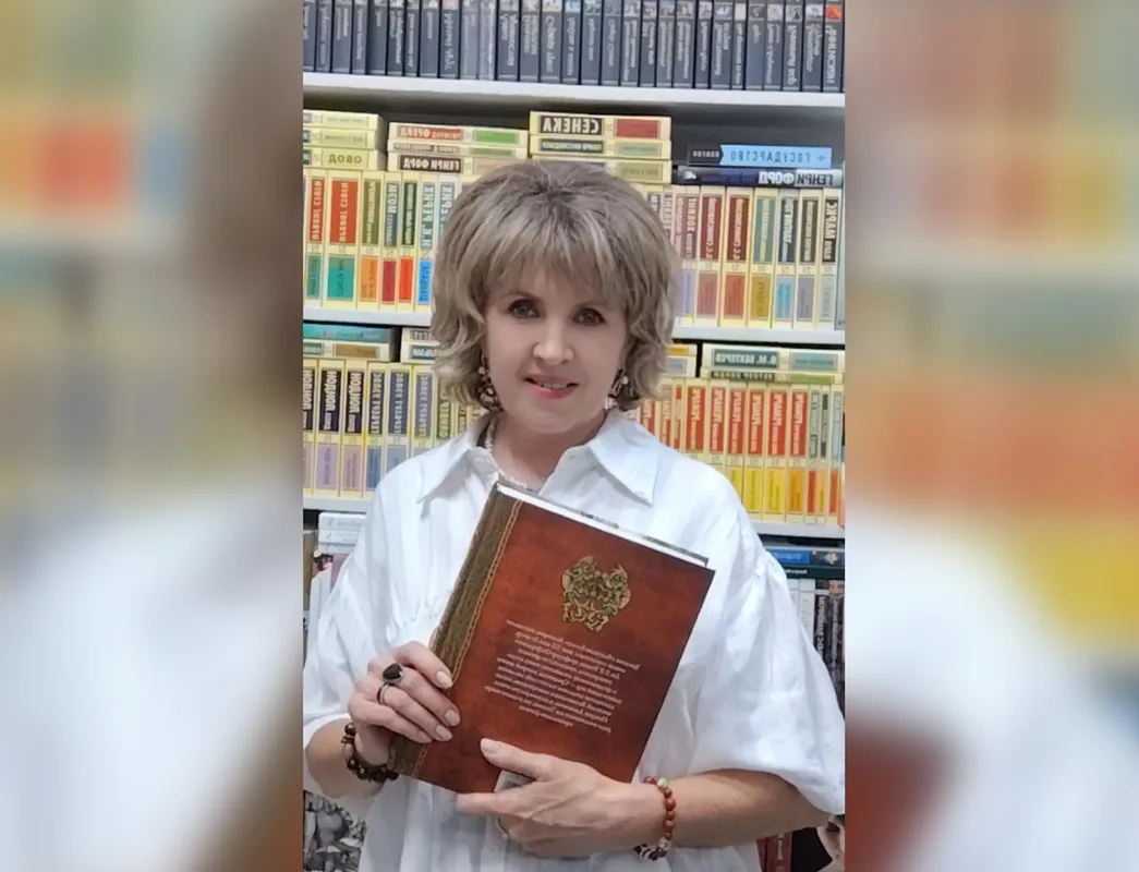 Женщина-продавец стоит за прилавком в книжном бутике, окруженная книгами на полках