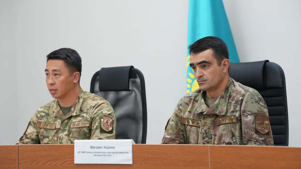 Сотрудник МЧС Казахстана у водоема с спасательным кругом, напоминая о важности соблюдения правил безопасности.