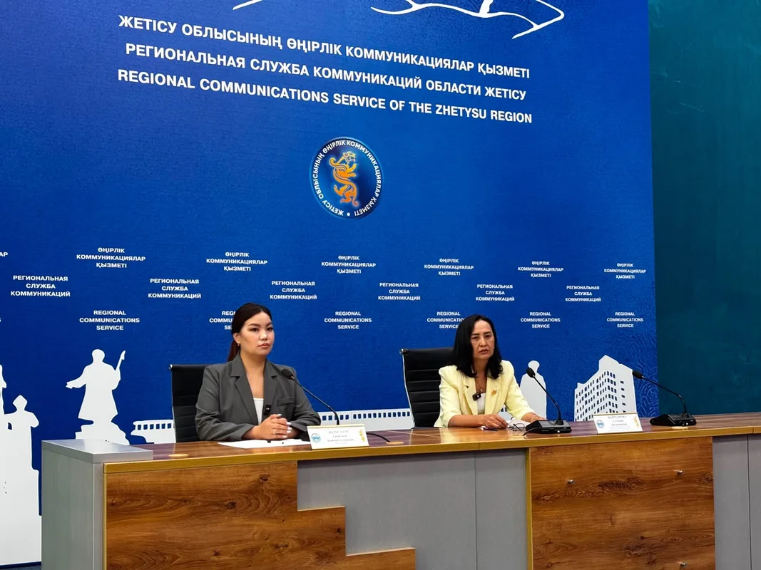 Сотрудник АЗРК Жетісу проверяет документы в офисе молочной компании на фоне полей.
