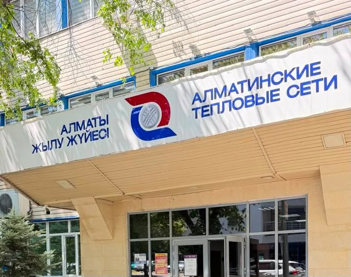 Жилой дом в Алматы, на фоне которого изображен логотип коммунальной службы, символизирующий оплату долгов.
