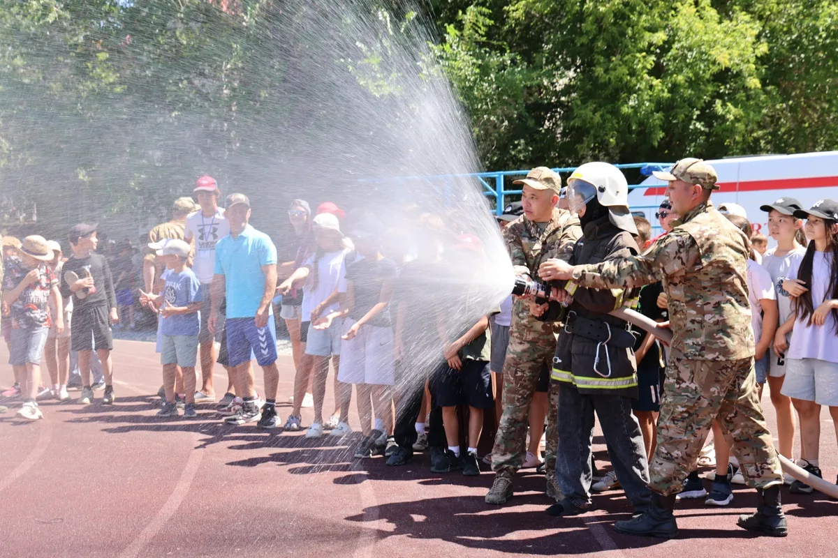 Спасатели проводят обучающее занятие для группы детей в летнем лагере на открытом воздухе.