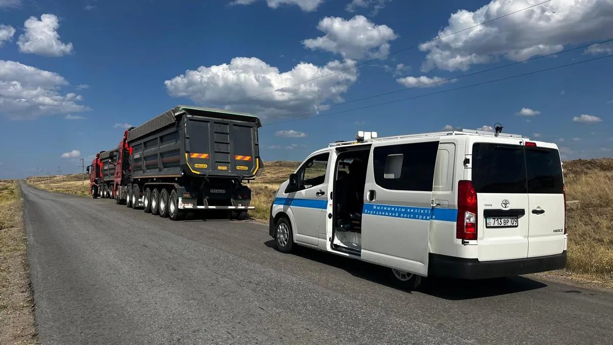 Грузовой автомобиль на дороге под контролем транспортной инспекции, символизирующий проверку тяжеловесного транспорта в Казахстане.