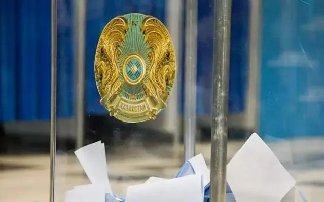 Человек опускает бюллетень в урну для голосования на избирательном участке