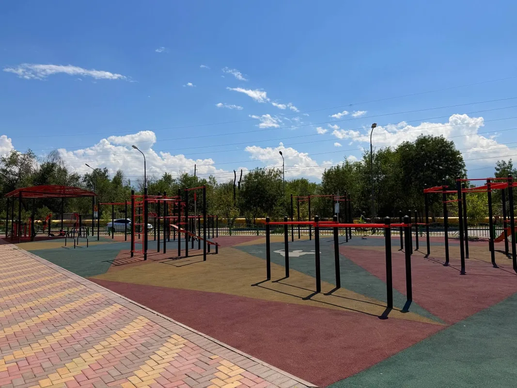 Обновленное общественное пространство в микрорайоне Алтын Бесік Алматы с футбольным полем, детской площадкой и зелёными насаждениями.