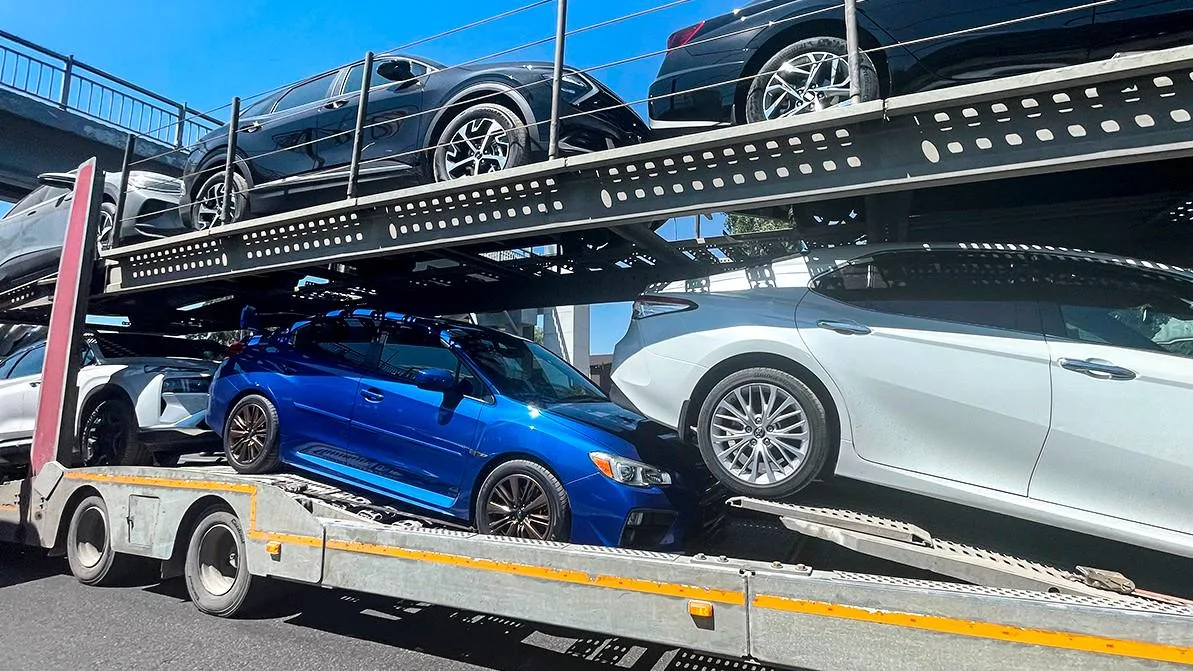 Ряд новых автомобилей различных марок, выставленных в автосалоне, символизирующих грядущее повышение цен на рынке Казахстана.