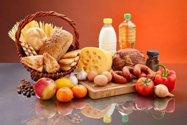 Корзина с социально значимыми продуктами: лук, картофель, яблоки на прилавке магазина