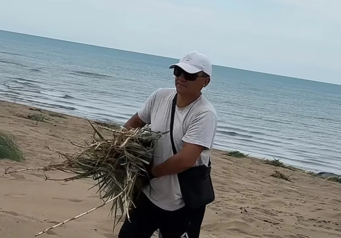 Группа людей убирает мусор на побережье озера Балхаш, готовя территорию для пляжа