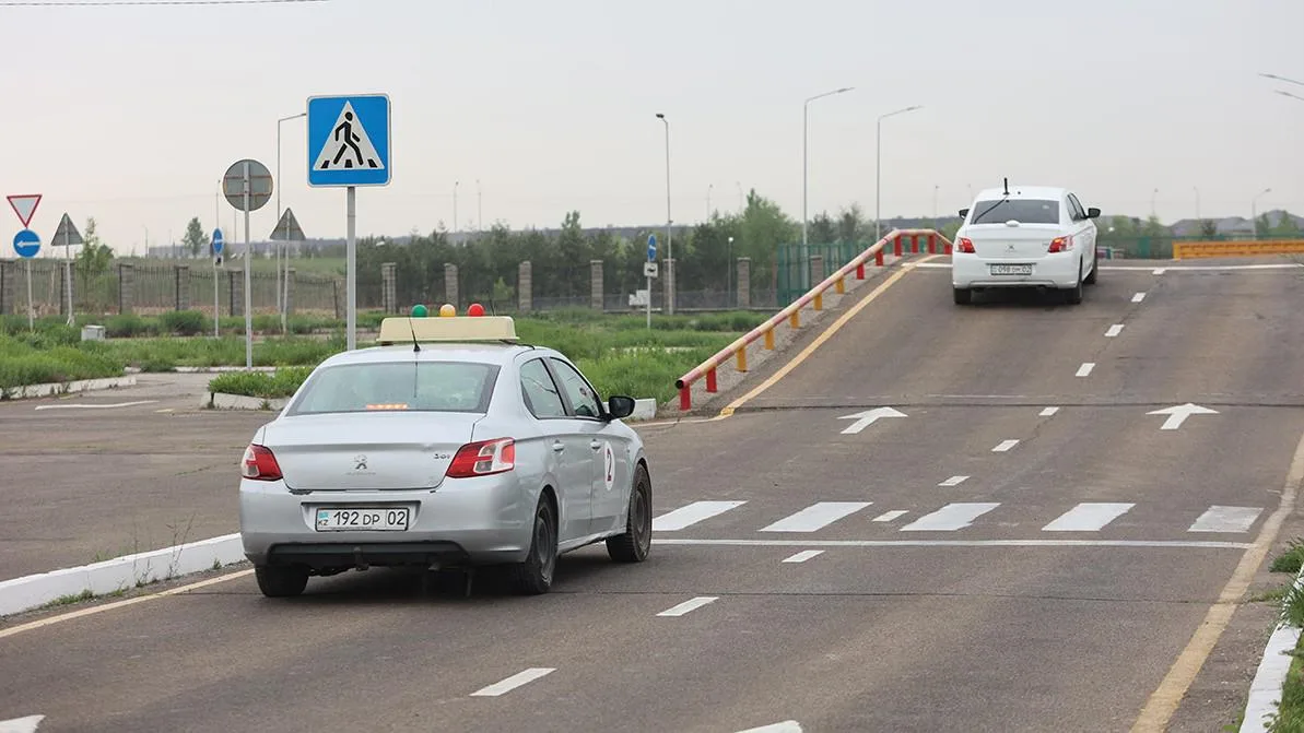 Курсант за рулём учебного автомобиля на площадке для практического экзамена по вождению в специализированном ЦОНе.