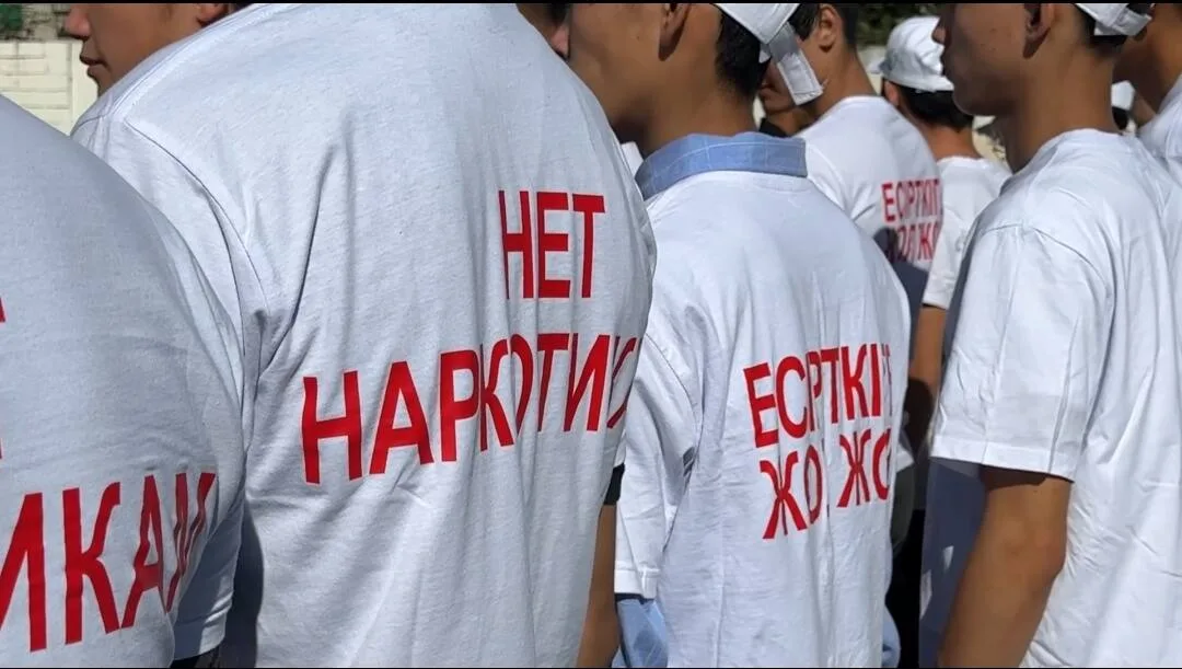 Волонтеры и полицейские закрашивают наркограффити на стене в области Жетісу