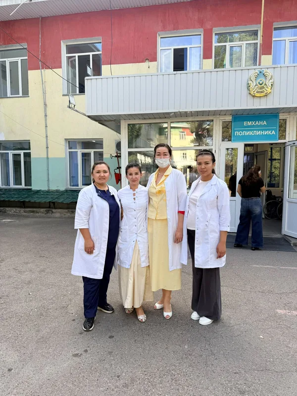 Мобильная медицинская группа осматривает пациентов в сельской больнице Алматинской области, врач консультирует женщину.