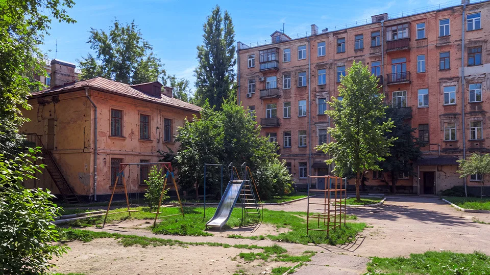 Снос старого дома, на фоне которого видны остовы новых строящихся зданий, символизирующий процесс реновации жилищного фонда.