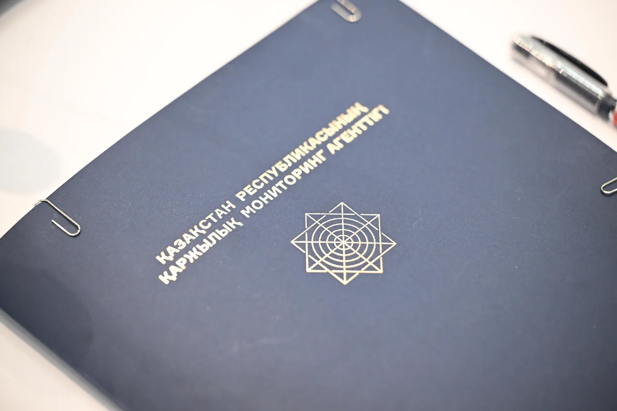 Сотрудники АФМ работают с документами на фоне стопки денег и ювелирных изделий, изъятых у незаконной сети ломбардов.