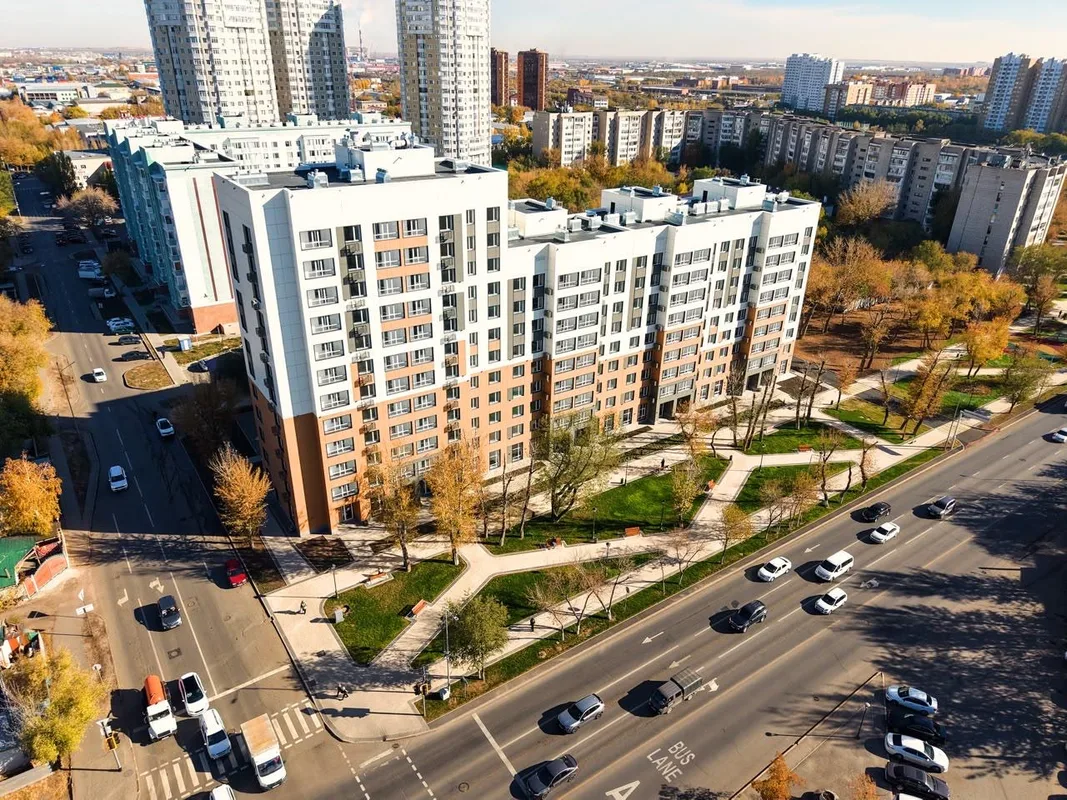 Новый сквер в Астане с вымощенными дорожками и детской площадкой, окруженный зелёными насаждениями.