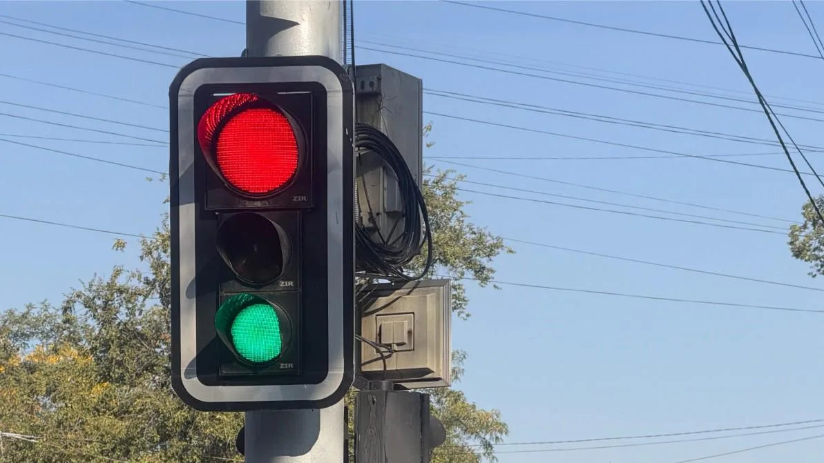 Оживлённый перекрёсток в Алматы без работающих светофоров, где автомобили пытаются проехать, создавая заторы и неупорядоченное движение.
