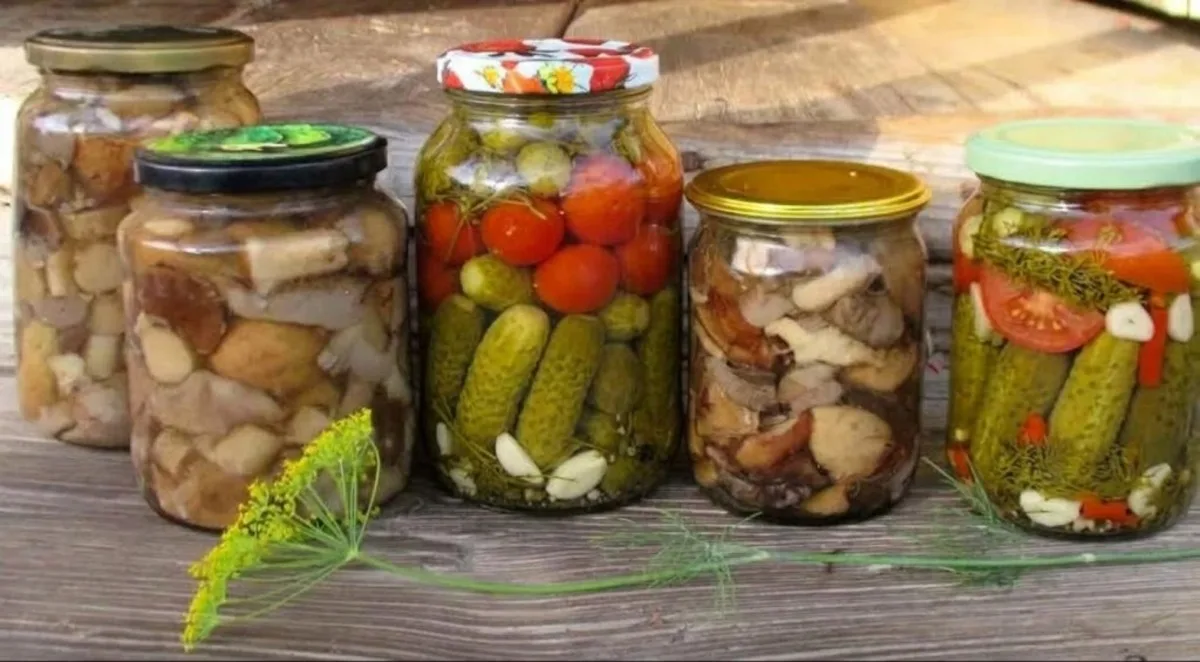 Банки с домашними консервами и овощами на деревянном столе